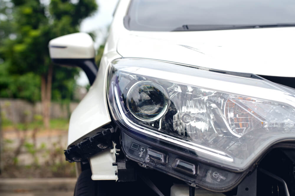 Front of white car in total loss accident that needs car insurance