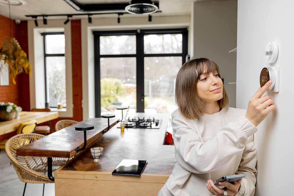 Woman at home adjusting a thermostat