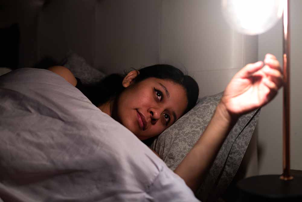 Woman turning off a light while lying in bed